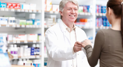 Male pharmacist dispensing tablets to a woman